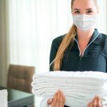 camareira trabalhando em um hotel usando uma mascara facial