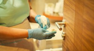 Maid desinfecta y limpia la manija de la puerta de la habitación del hotel con toallitas antibacterianas.